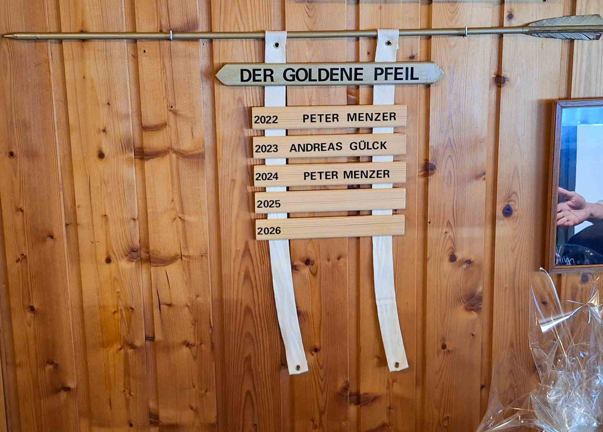 Der Goldene Pfeil an einer Holzwand.